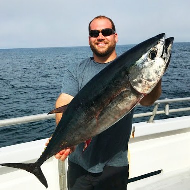 a man holding a fish on a boat in a body of water