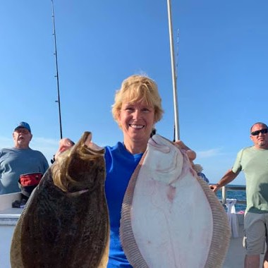 a group of people standing next to a man holding a fish
