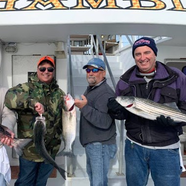 a group of people standing next to a person holding a fish