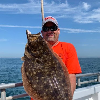 a man holding a fish on a boat in a body of water