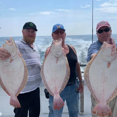 a group of people standing next to a person holding a fish