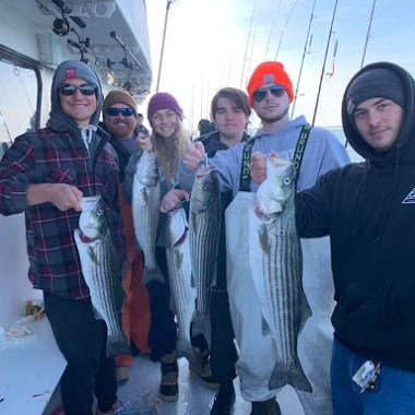 a group of people standing next to a man holding a fish