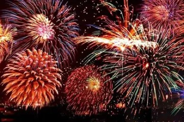 Colorful fireworks display in night sky over a cityscape.